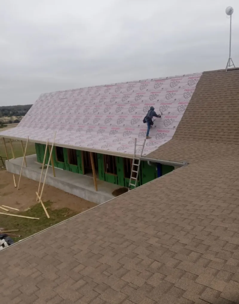 Worker preparing underlayment for a metal roof installation in Newark